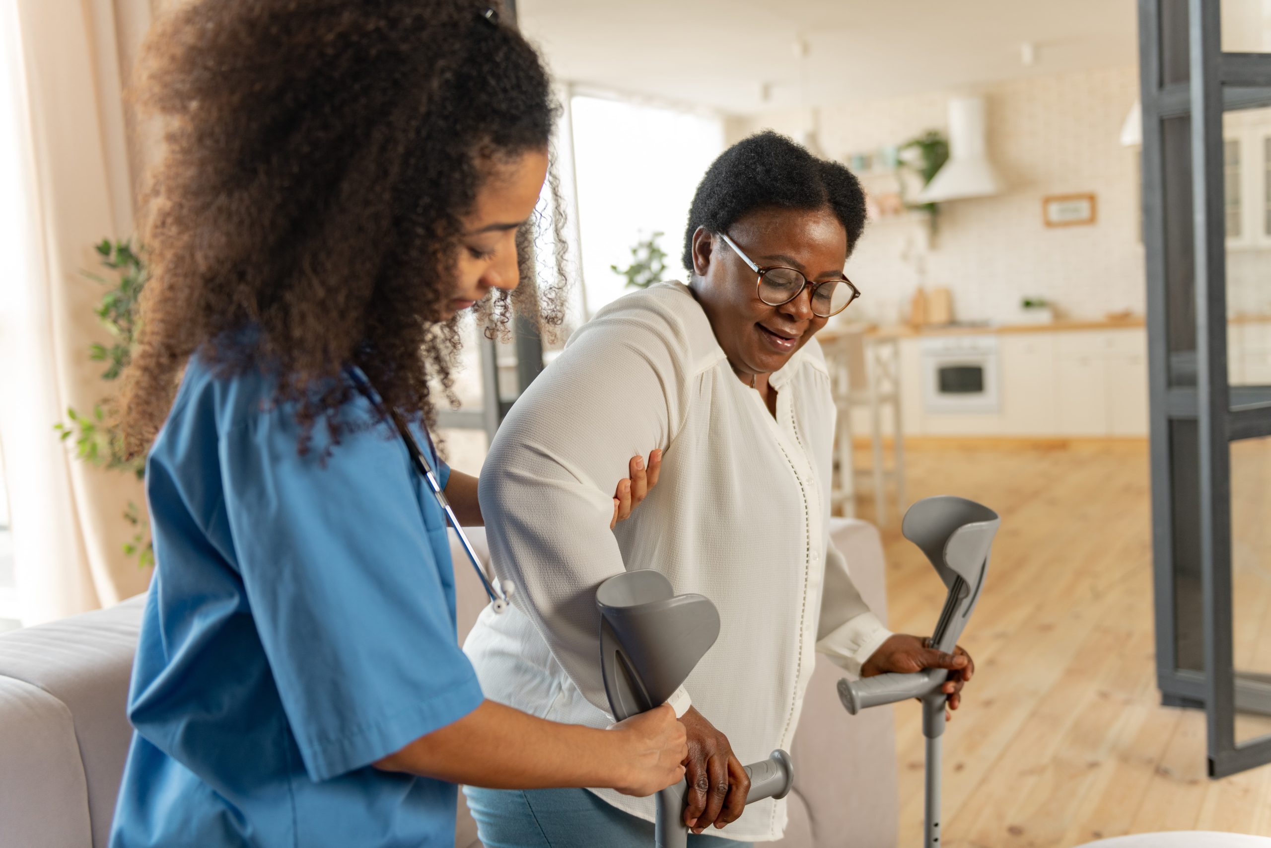 giving-crutches-curly-young-dark-haired-nurse-giving-crutches-aged-woman-wearing-glasses-after-leg-surgery (1)